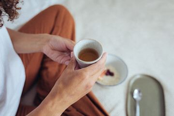 Frau im Schneidersitz mit Tee und Frühstück im Bett