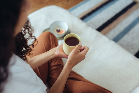 Frau im Schneidersitz mit Tee und Fr&uuml;hst&uuml;ck im Bett