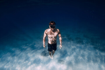 Fototapeta na wymiar Man freediver underwater in blue ocean in Hawaii. Sporty man