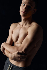 athlete with a naked torso crossed his arms over his chest on a black background