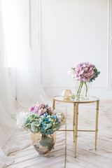 Tender simple  interior in light colors with tule, bouquets of artificial hydrangea and elegant  mirror table on light parquet floor