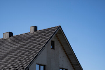 Brown corrugated metal profile roof installed on a modern house. The roof of corrugated sheet. Roofing of metal profile wavy shape. Modern roof made of metal. Metal roofing.