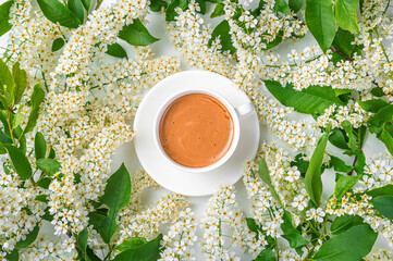 A white cappuccino cup among the flowering branches.
