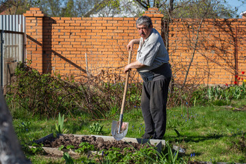 Caucasian Senior man with shovel digging garden bed or farm
