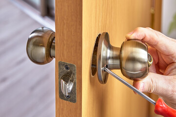 DIY installation of door lock mechanism with handles in new wood panel.