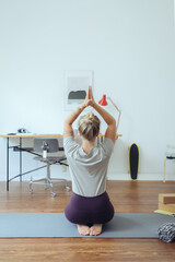 Frau macht Yoga im Homeoffie zur Entspannung und als Ausgleich 