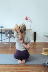 Frau macht Yoga im Homeoffie zur Entspannung und als Ausgleich 