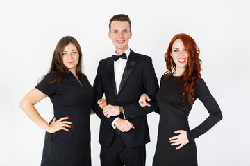 Young man and two women in black on a white background. Trio band of  actors performing on the stage. Smiling team of man and two women on white background with copy space