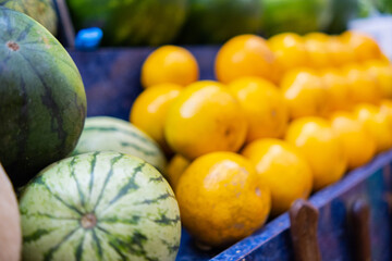 Close-up of colorful fruit stand with watermelons and a pile of oranges