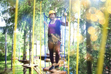 Obraz na płótnie Canvas extreme vacation, girl in a yellow helmet rope park active holidays in the forest