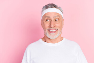 Photo portrait of senior man in headband smiling happy looking empty space isolated pastel pink color background