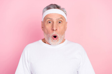 Photo portrait of elder man in headband staring amazed with opened mouth isolated on pastel pink color background