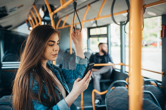 Woman using a samrtphone while standing in a moving bus