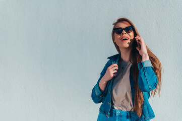 Young beautiful woman using a smartphone and wearing jeans and sunglasses