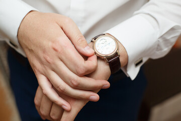 Groom's morning. Wedding accessories. Groom or a business man puts a watch on his hand