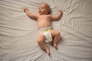 Adorable baby wearing only diapers lying on his back
