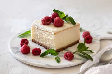 Cheesecake with raspberries garnished with mint. On a light background