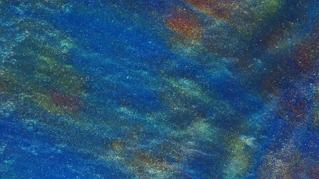 Fluid art. Liquid abstractions. Starry gold dust. Abstract bright red and light pastel streams with gold dust spread across the plane on a blue background. Marble texture.