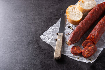 Spanish chorizo sausage and bread on black stone. Copy space