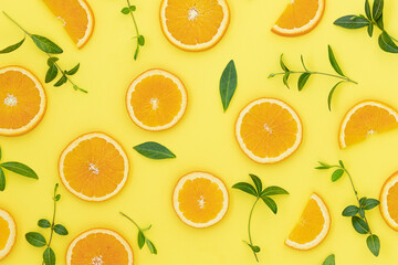 Summer bright background with oranges and green leaves on the yellow surface