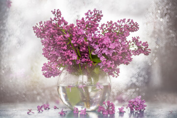 A bouquet of lilacs in a transparent vase. Artistic photo with sparkling bokeh and very soft selective focus. Shallow depth of field for an artistic idea. Spring bouquet.