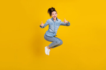 Full length body size photo young pretty girl jumping up showing thumb up gesture isolated vivid yellow color background