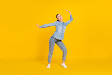 Fototapeta na wymiar Full length photo of funny charming young woman wear denim shirt smiling dancing isolated yellow color background
