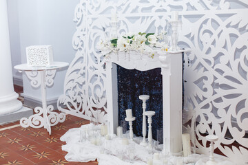 Elegant white fireplace on beautiful white toreutic background. Elegant wedding ceremony