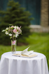 Bible, vine and wedding rings on a table in a garden. Reading outdoor. Relax on air. Poetic. Wedding ceremony outdoor. Wedding ceremony decoration in the garden.