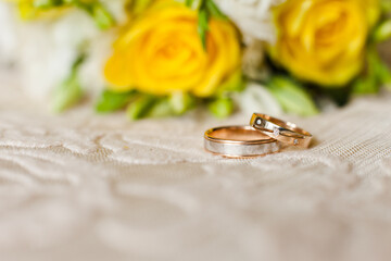 Obraz na płótnie Canvas Two wedding rings on a background from yellow roses