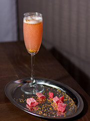 Alcoholic cocktail in a beautiful glass on a tray with candied fruits. Summer menu concept.
