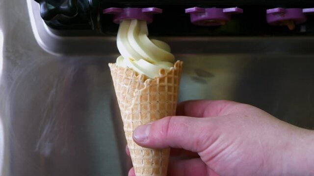 The process of filling waffle cone with ice cream. Man making ice cream