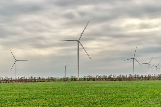 Wind Turbines Generating Electricity In A Green Field. Green Power Generation Concept.