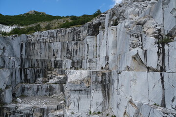 Wall of a white marble quarry under the mountain.In this area there are some quarries of white marble that is extracted from the mountain with open-air quarries. Apuan Alps, Tuscany, Italy. 
