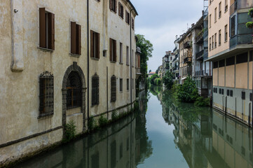 Fototapeta na wymiar Houses along a canal, mirroring into the water, in Padua in Italy, seen from the Ponte delle Toricelle.