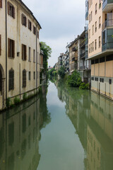 Fototapeta na wymiar Houses along a canal, mirroring into the water, in Padua in Italy, seen from the Ponte delle Toricelle