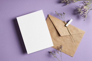 Invitation or greeting card mockup with envelope and dry limonium flowers on lavender color...