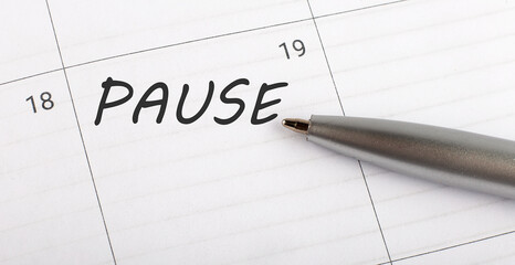 Text PAUSE on calendar planner to remind you an important appointment with a pen on isolated white background.