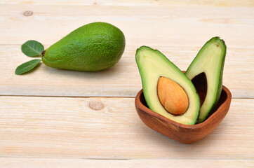halved avocado in a wooden bowl