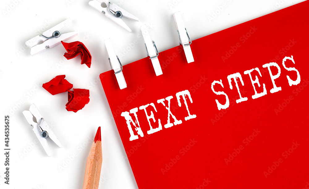 Aufkleber next steps text on red paper with office tools on white background