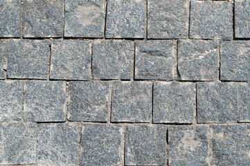 An old stone pavement. The old road. Stone masonry. Gray granite. Square cut stone masonry. Roads of the old city.