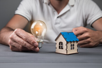 Obraz na płótnie Canvas a man holding a light bulb and a house