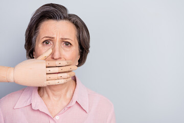 Photo of unhappy upset old woman hand cover close mouth silence empty space isolated on grey color...