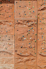 Street artificial rock climbing wall close-up view various colored grips. Colorful footholds for training. Orange climbing wall background