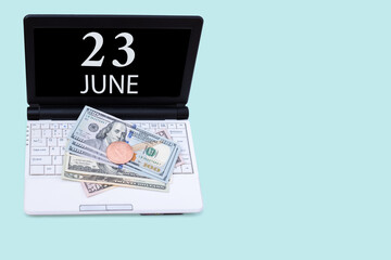 Laptop with the date of 23 june and cryptocurrency Bitcoin, dollars on a blue background. Buy or sell cryptocurrency. Stock market concept.