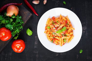Classic italian pasta penne alla arrabiata with basil and freshly grated parmesan cheese on dark...