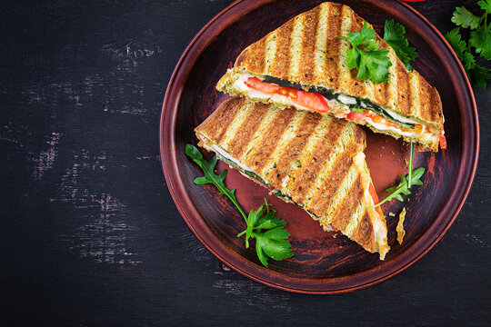 Vegetarian Sandwich Panini With Spinach Leaves, Tomatoes And Cheese On A Dark Table. Toast With Cheese. Top View, Overhead, Copy Space