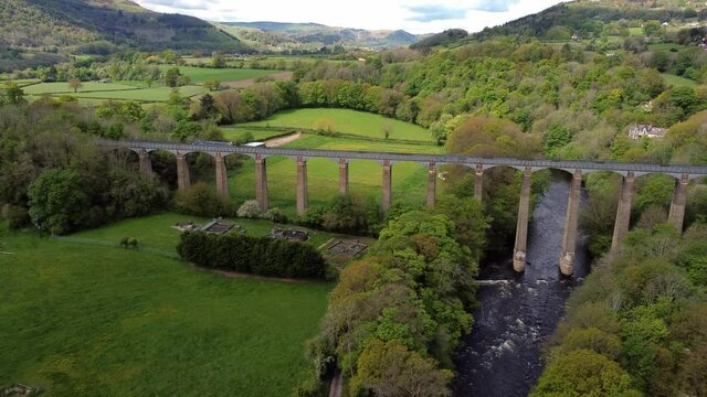 Aerial view Pontcysyllte aqueduct and River Dee canal narrow boat bride in Chirk Welsh valley countryside pull away left tilt up