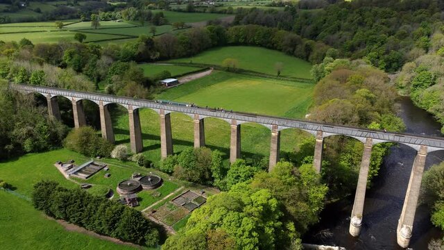 Aerial view Pontcysyllte aqueduct and River Dee canal narrow boat bride in Chirk Welsh valley countryside rising pull back