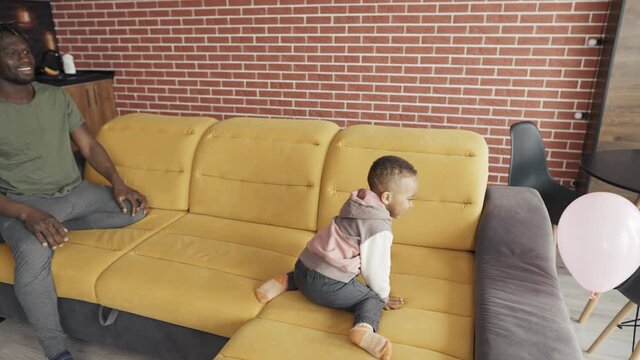 African-American father playing with little boy at the living room